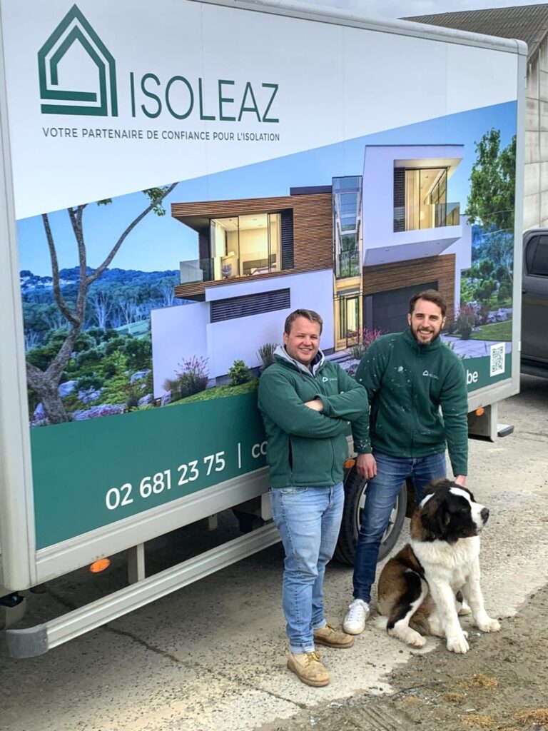 Brieuc Thoumsin en Pierre Guinsbourg poseren voor een vrachtwagen met reclame voor Isoleaz. Aan hun voeten zit een grote hond.