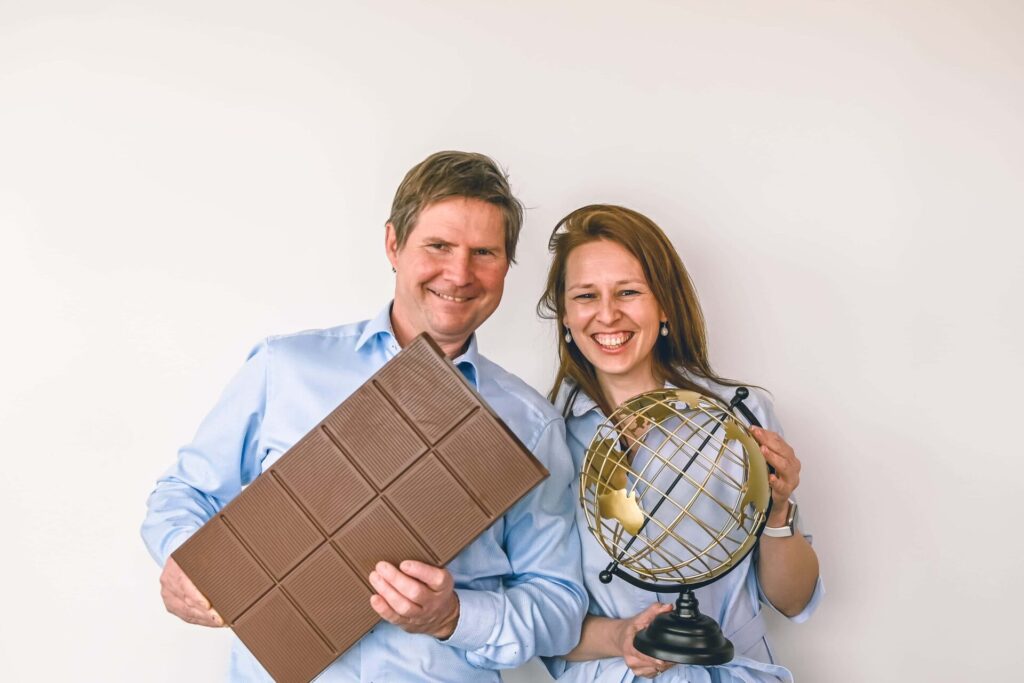 Foto van Koen Klingele die poseert met een reuzereep chocolade en Eline Blanchaert die poseert met een wereldbol